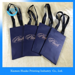 La cinta de lujo maneja las bolsas de papel de las compras del regalo con su propio logotipo 
